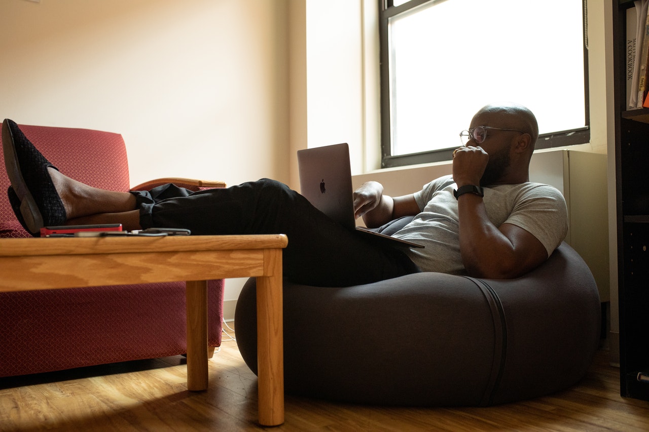 Man working on his laptop while sitting on a bean bag