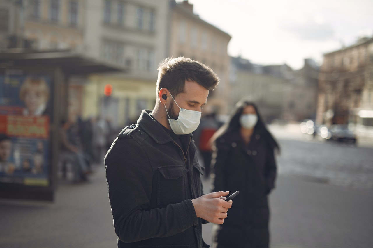 Man with facemask browsing on his phone while in public